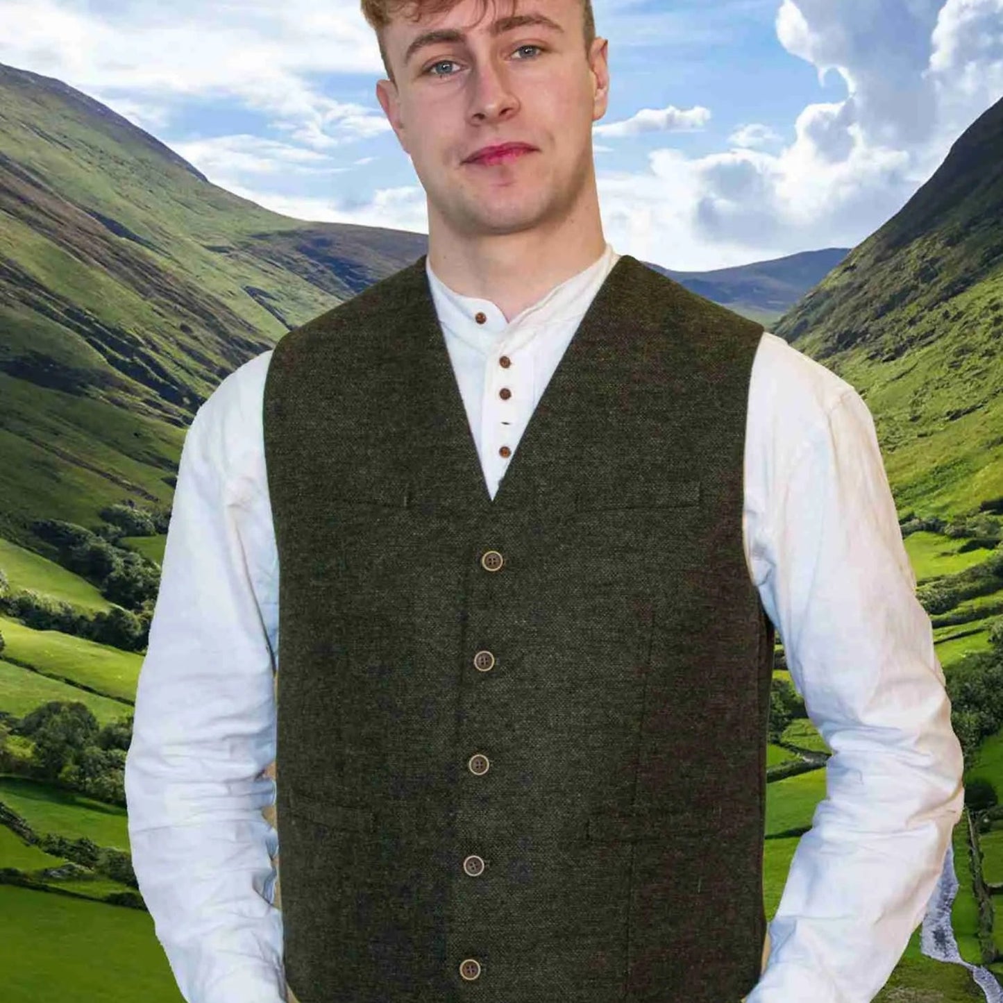 Man wearing a green vest over a white shirt with a mountainous landscape in the background