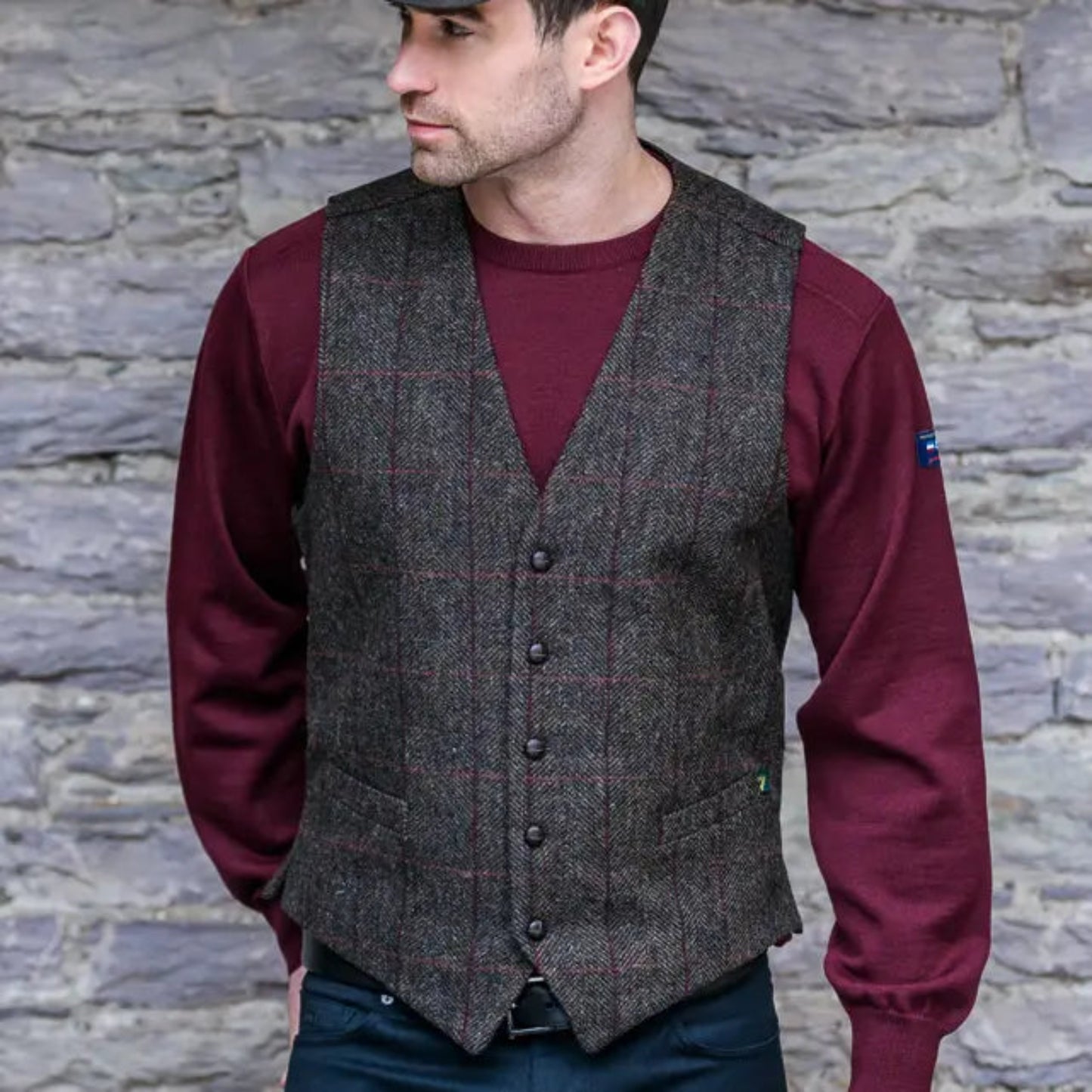 A man wearing a blue shirt and a brown tweed vest with a button-up front.