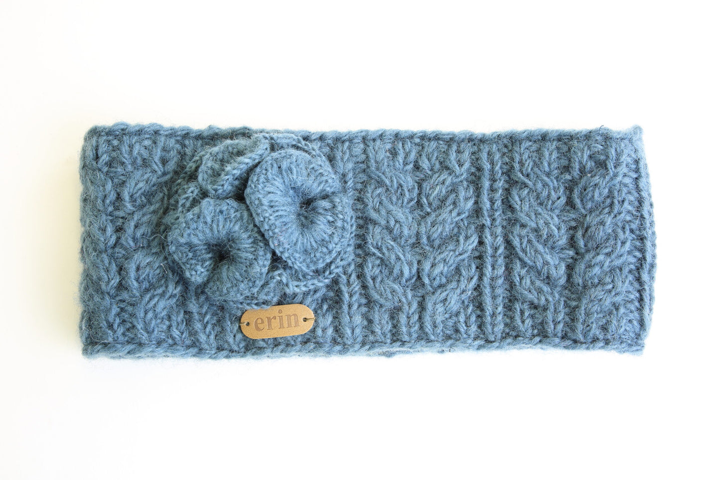 Blue knitted headband with cable pattern on a white background