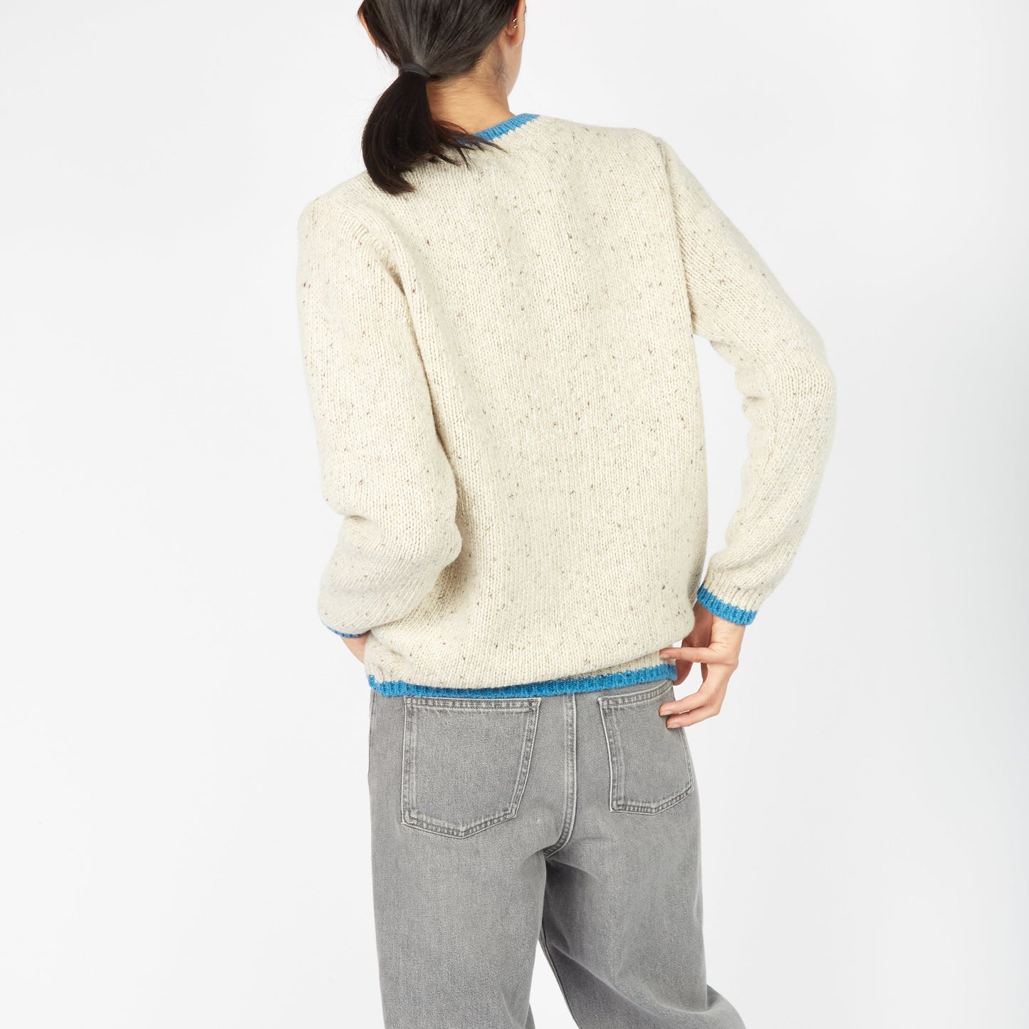 Person wearing a cream sweater and gray pants on a white background