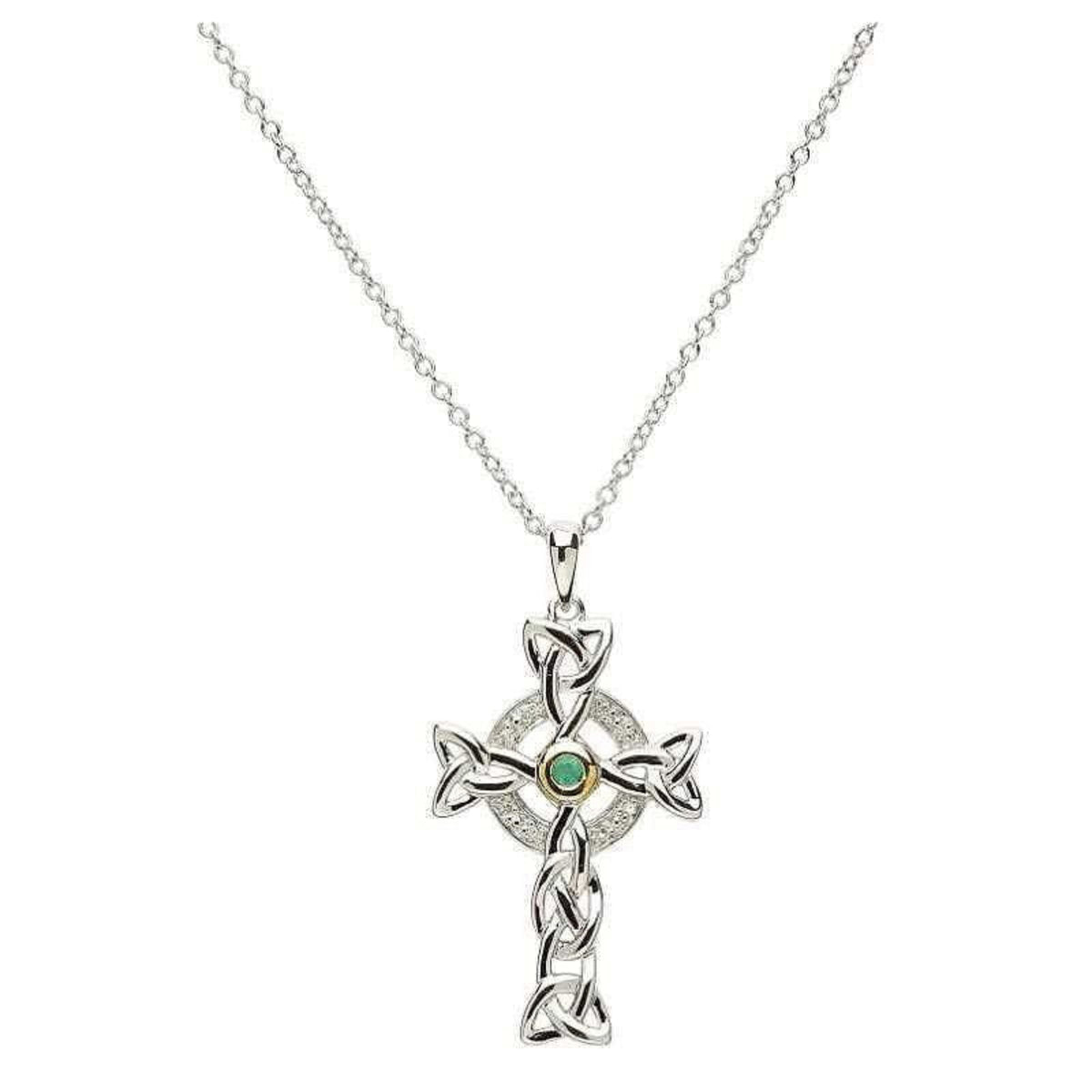 A silver Celtic cross necklace with a trinity knot design, encrusted with small diamonds and a central emerald.