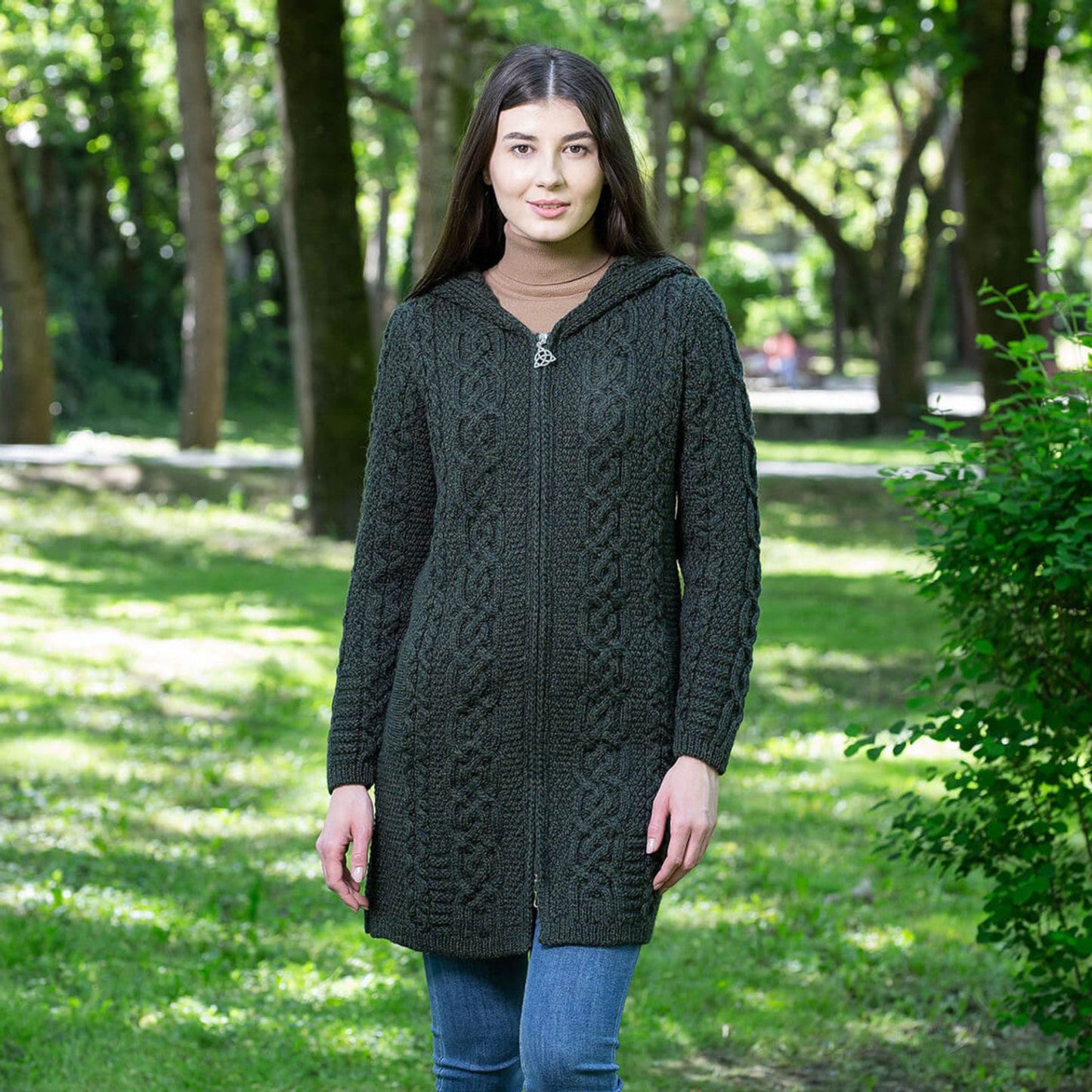 Woman wearing a dark green cable knit hoodie in a park setting