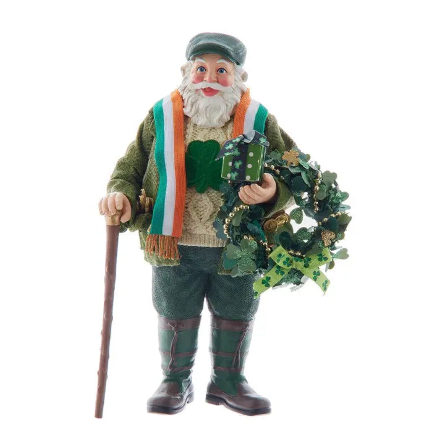 A St. Patrick's Day decorative figurine of an Irish gentleman with a white beard, wearing a green cap, green jacket, and green plaid trousers, holding a green shamrock wreath and a walking cane, isolated on a white background.