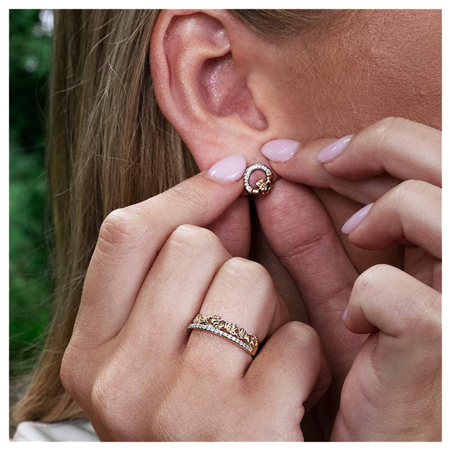 Close-up of a woman wearing a gold claddagh earring in her ear.