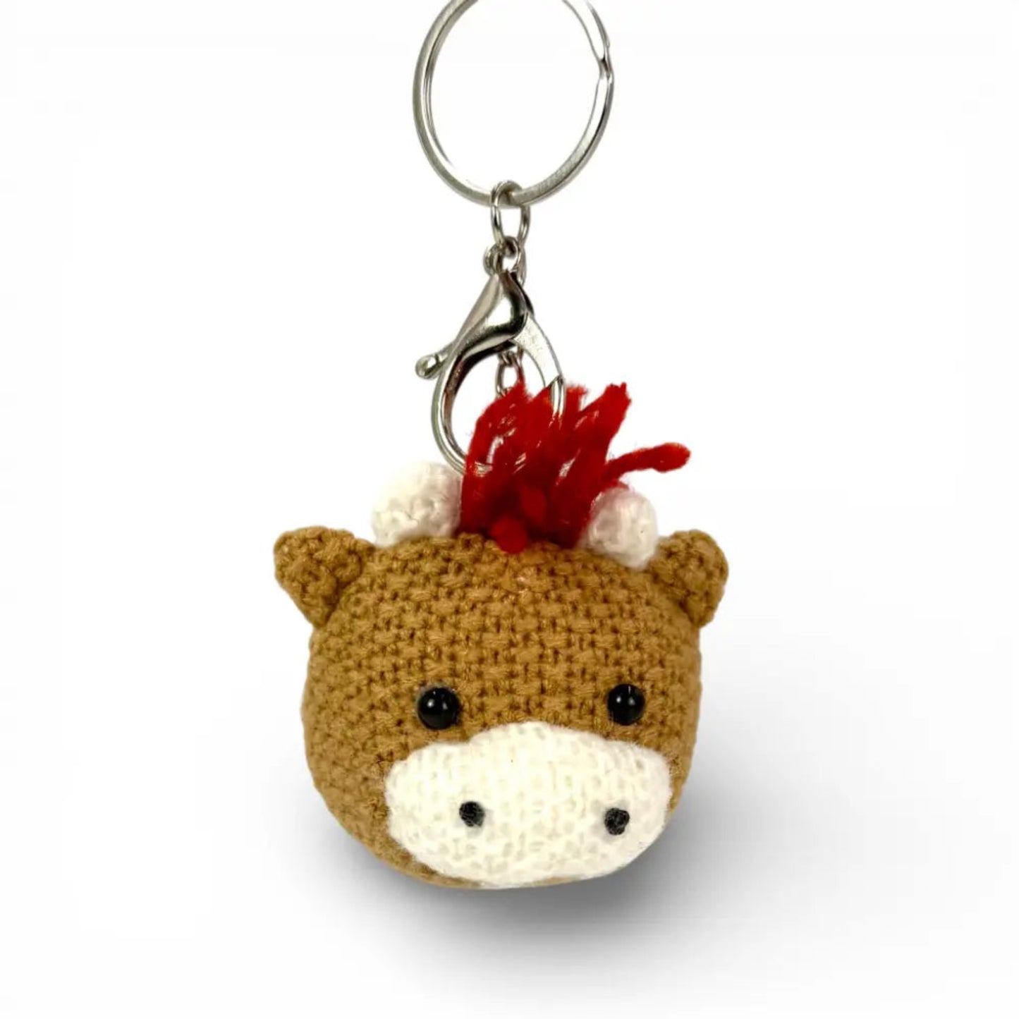Crocheted horse head keychain with a red mane on a white background