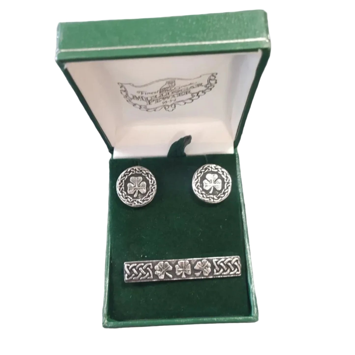Silver jewelry set with shamrock design in a green box on a textured surface