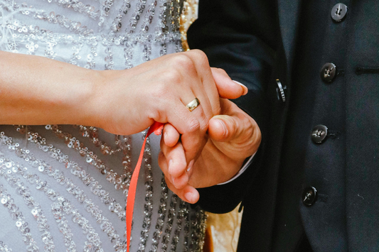 bride and groom holding hands with handfasting ribbon