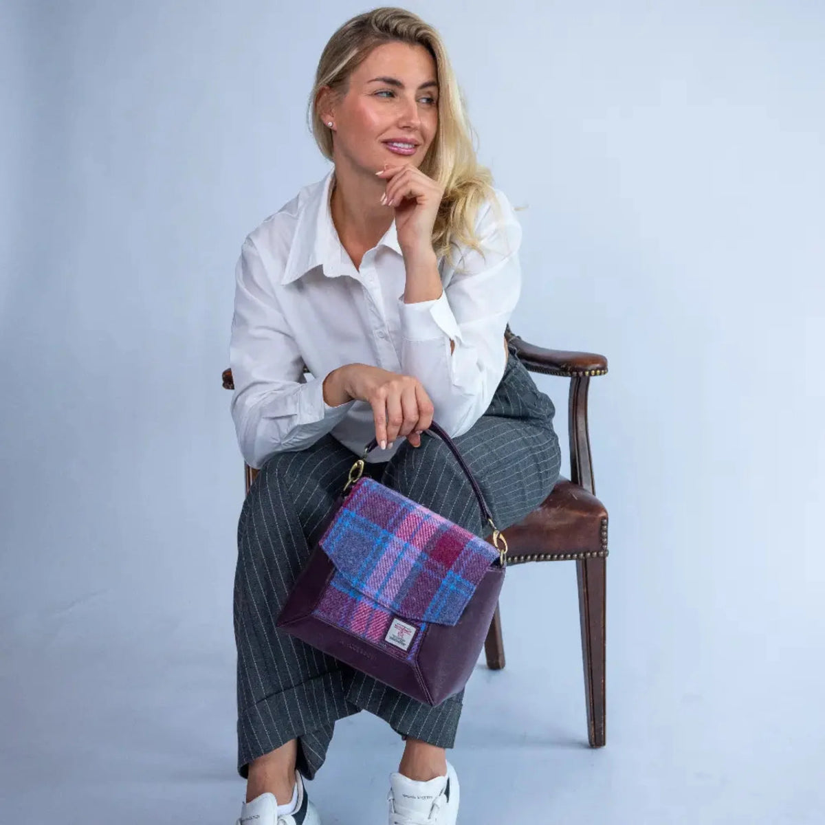 Woman holding a plaid handbag against a plain background
