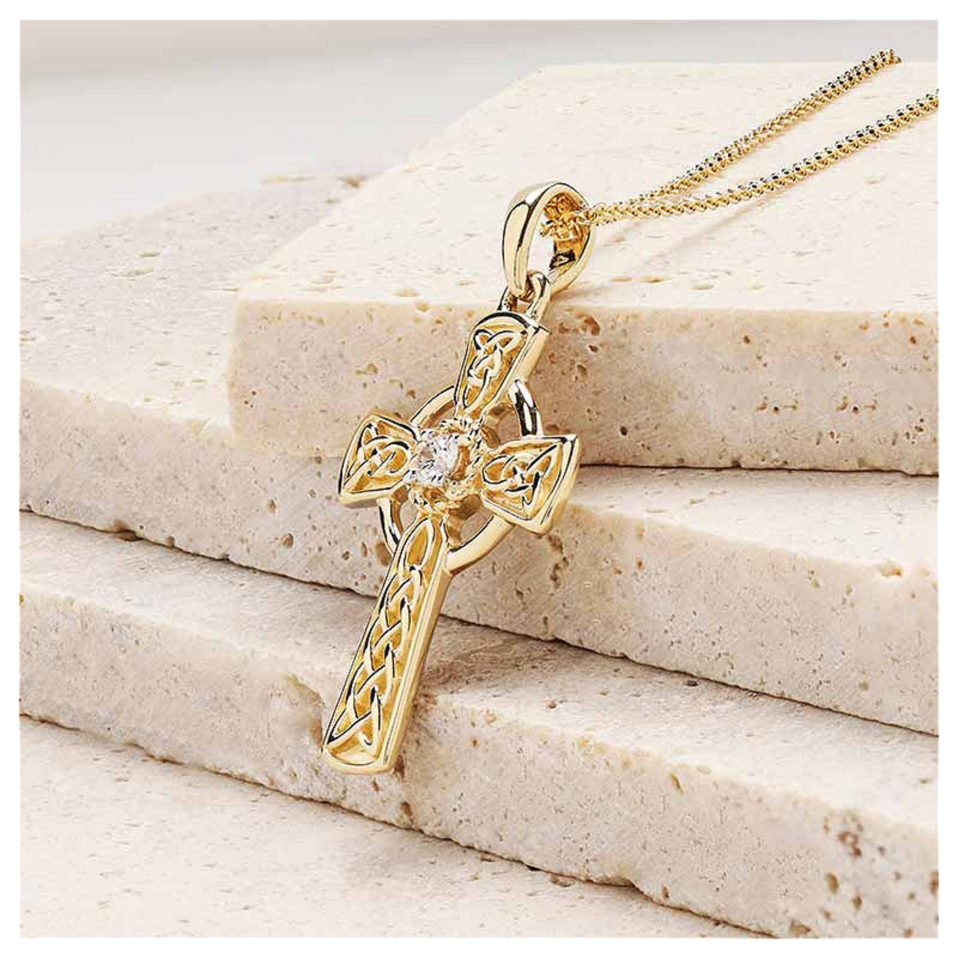 Gold celtic cross pendant sitting on a marble surface