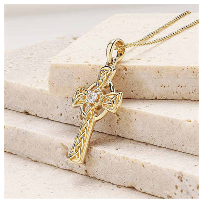 Gold celtic cross pendant sitting on a marble surface