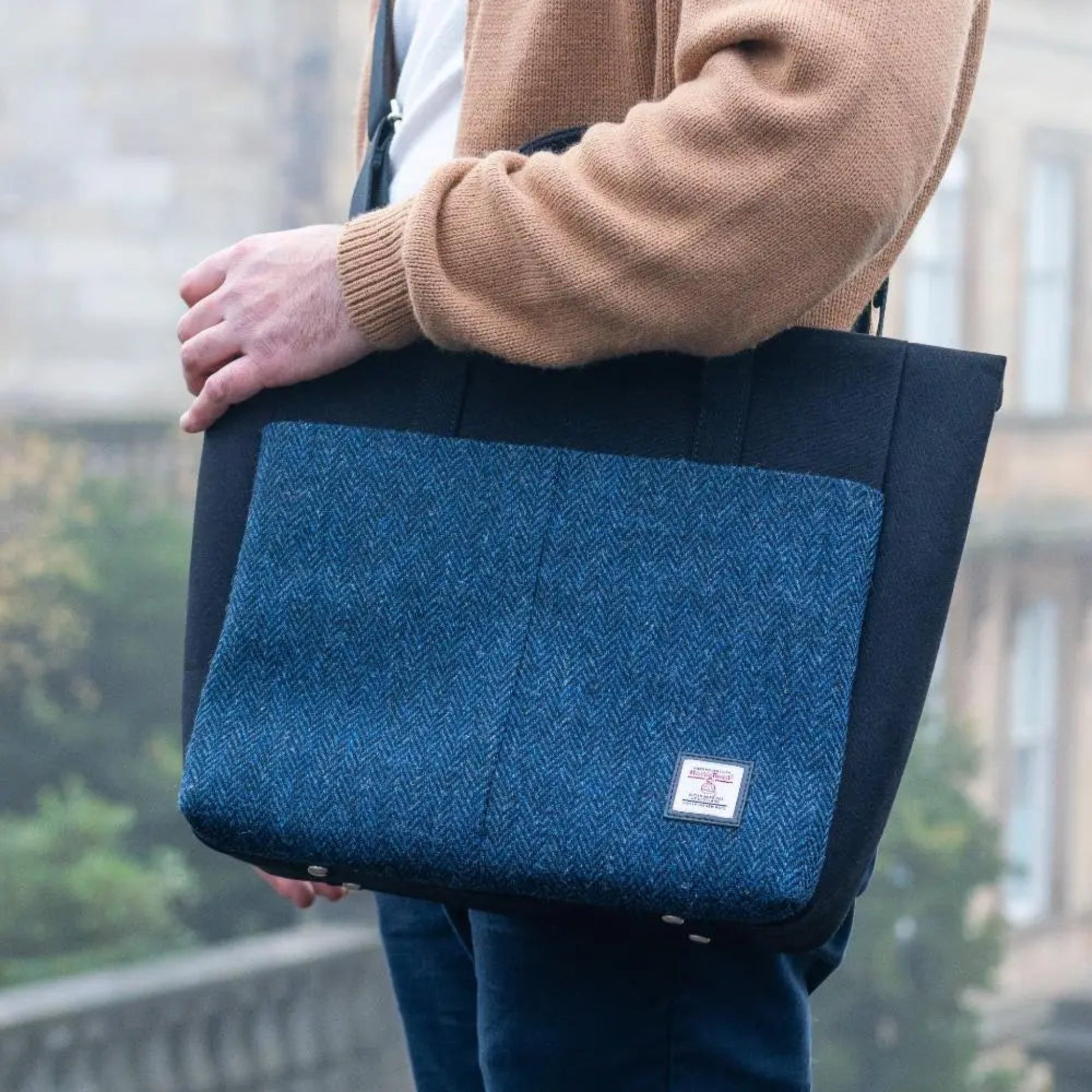 Person holding a blue and black bag with a blurred background