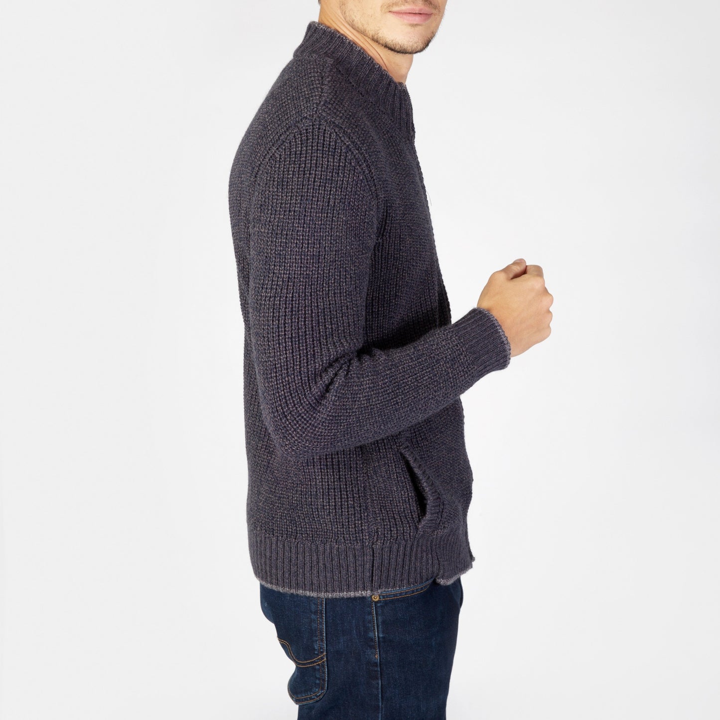 Person wearing a dark gray knitted sweater and jeans on a white background
