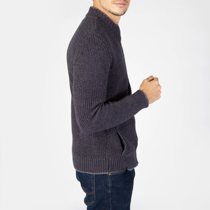 Person wearing a dark gray knitted sweater and jeans on a white background