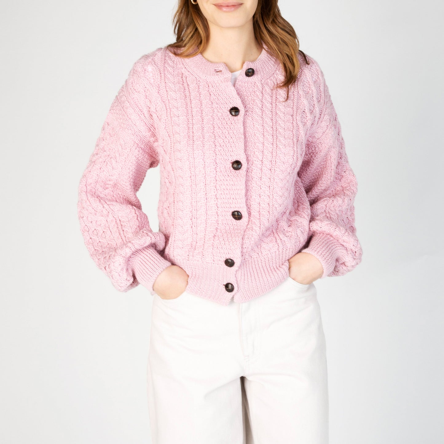 Pink knitted cardigan with button details on a white background