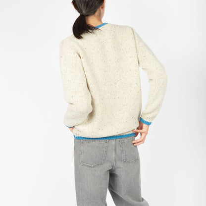 Person wearing a cream sweater and gray pants on a white background
