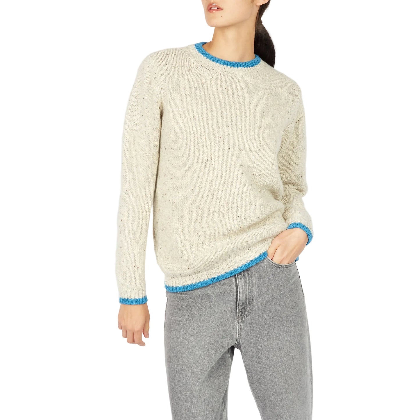 Person wearing a cream sweater with blue trim and gray pants on a white background