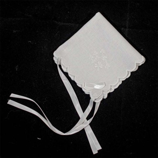 White baby bonnet with decorative bow on a black background