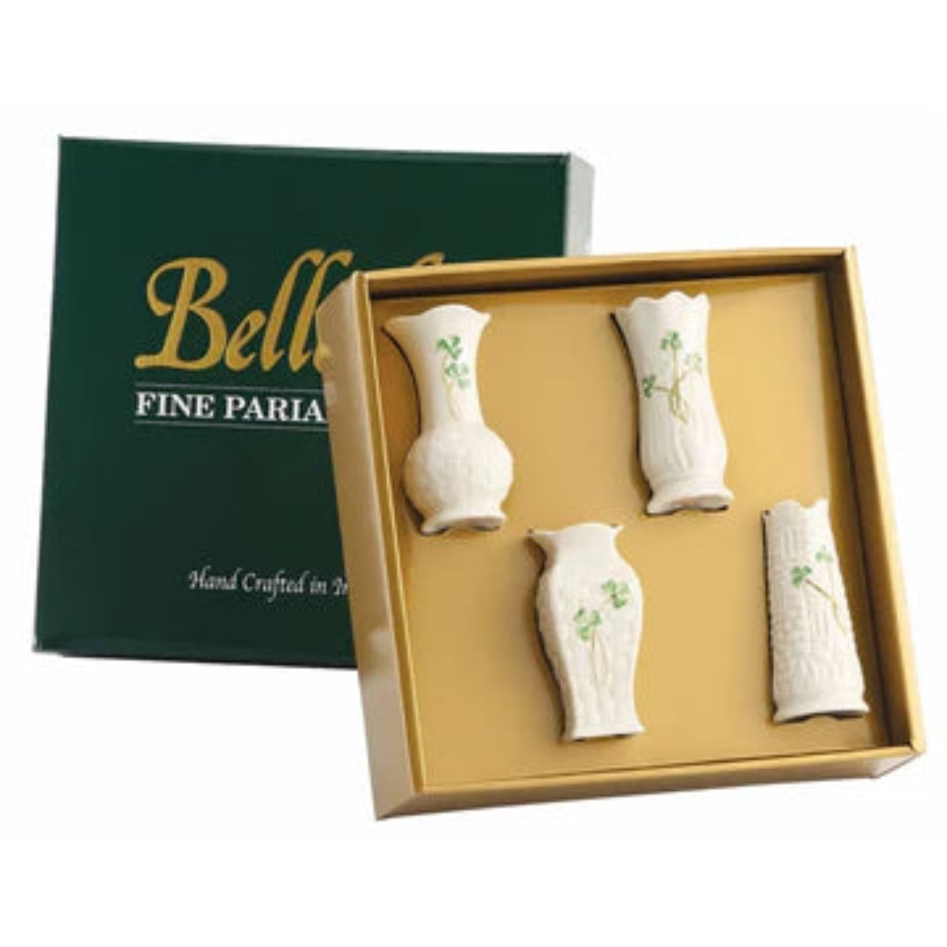 A set of four white ceramic mini vases with green shamrock patterns, presented in a gold-colored frame, alongside their green box packaging with 'Belleek Fine Parlary' branding.