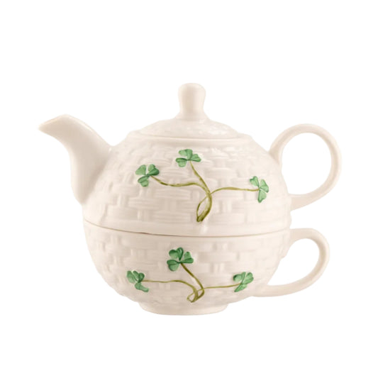 A white ceramic teapot with a shamrock design and green leaves on it.