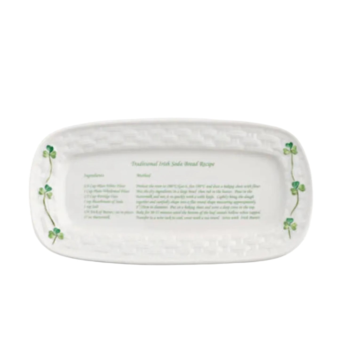 An oval-shaped ceramic tray with a white background featuring green shamrocks and text that provides a traditional Irish soda bread recipe.