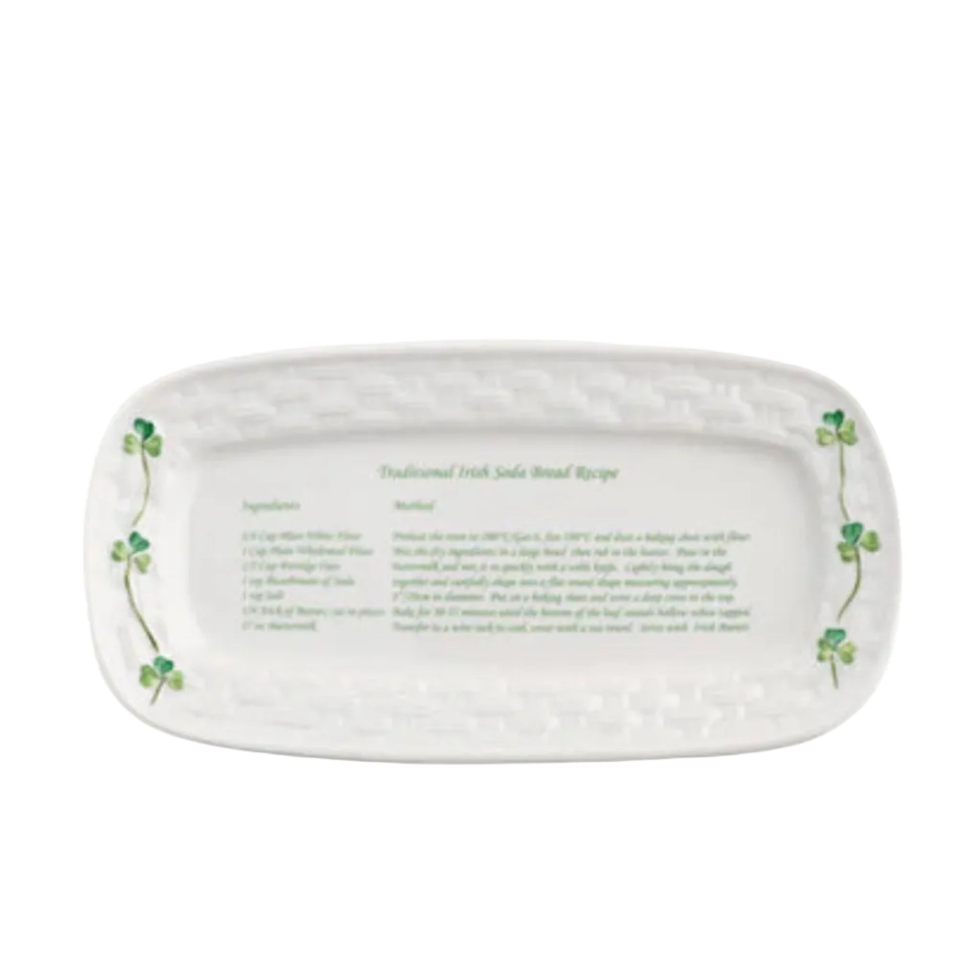 An oval-shaped ceramic tray with a white background featuring green shamrocks and text that provides a traditional Irish soda bread recipe.