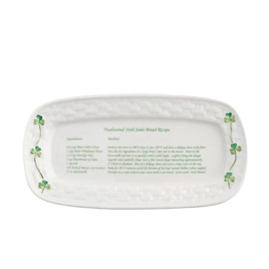An oval-shaped ceramic tray with a white background featuring green shamrocks and text that provides a traditional Irish soda bread recipe.