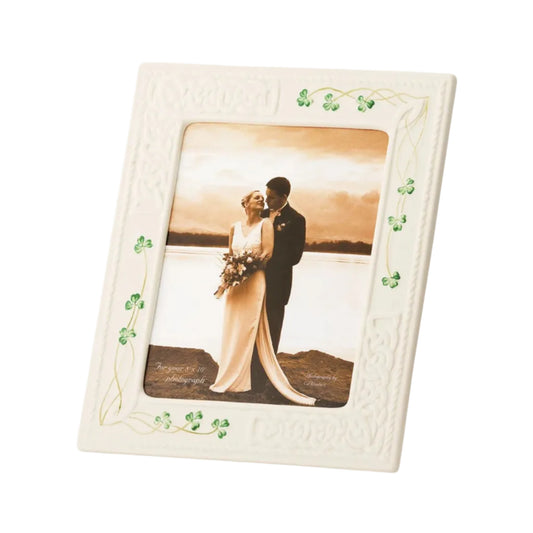 A white picture frame with a clover pattern around the border, featuring a couple embracing in the center.