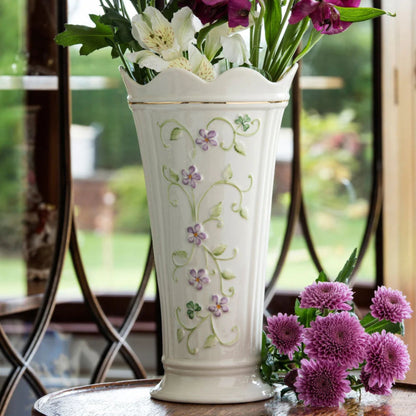Decorative vase with floral patterns on a table with flowers in the background