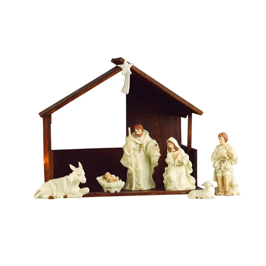 A ceramic nativity scene set featuring a dark brown wooden stable with white figurines of the Holy Family, a donkey, a sheep, and a star, isolated on a white background.
