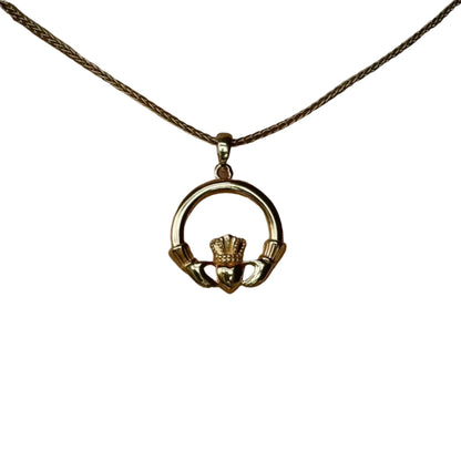 A golden necklace with a circular claddagh pendant.
