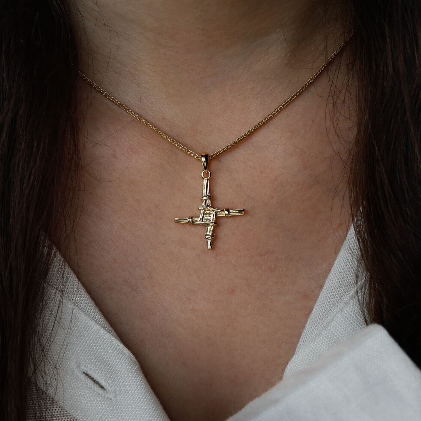 Close-up of a woman wearing a golden St. Brigid's cross necklace.