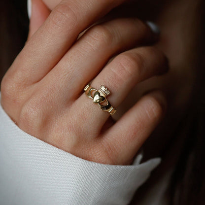CLose-up of a woman wearing a golden claddagh ring. 