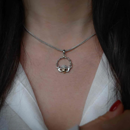 Close-up of a woman wearing a silver claddagh pendant necklace.