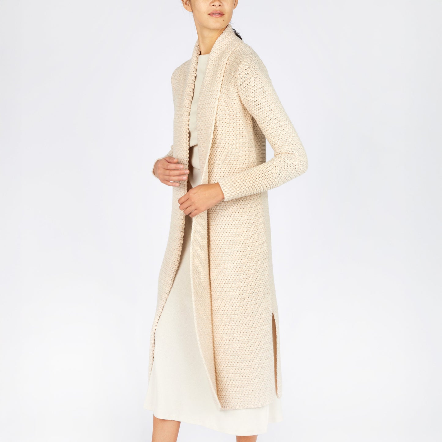 Person wearing a long cream cardigan on a white background