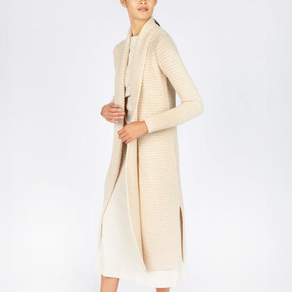 Person wearing a long cream cardigan on a white background