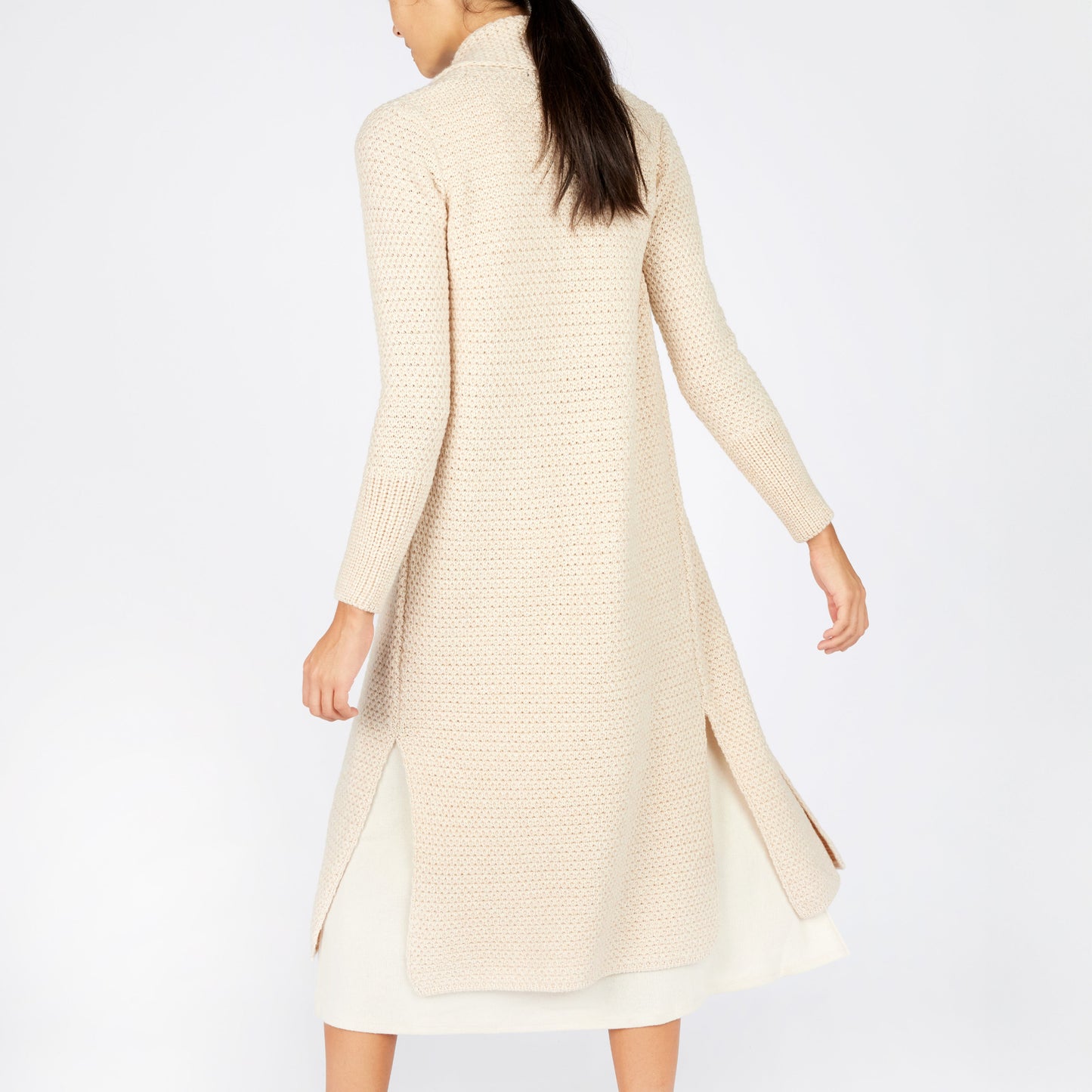 Woman wearing a long beige cardigan on a white background