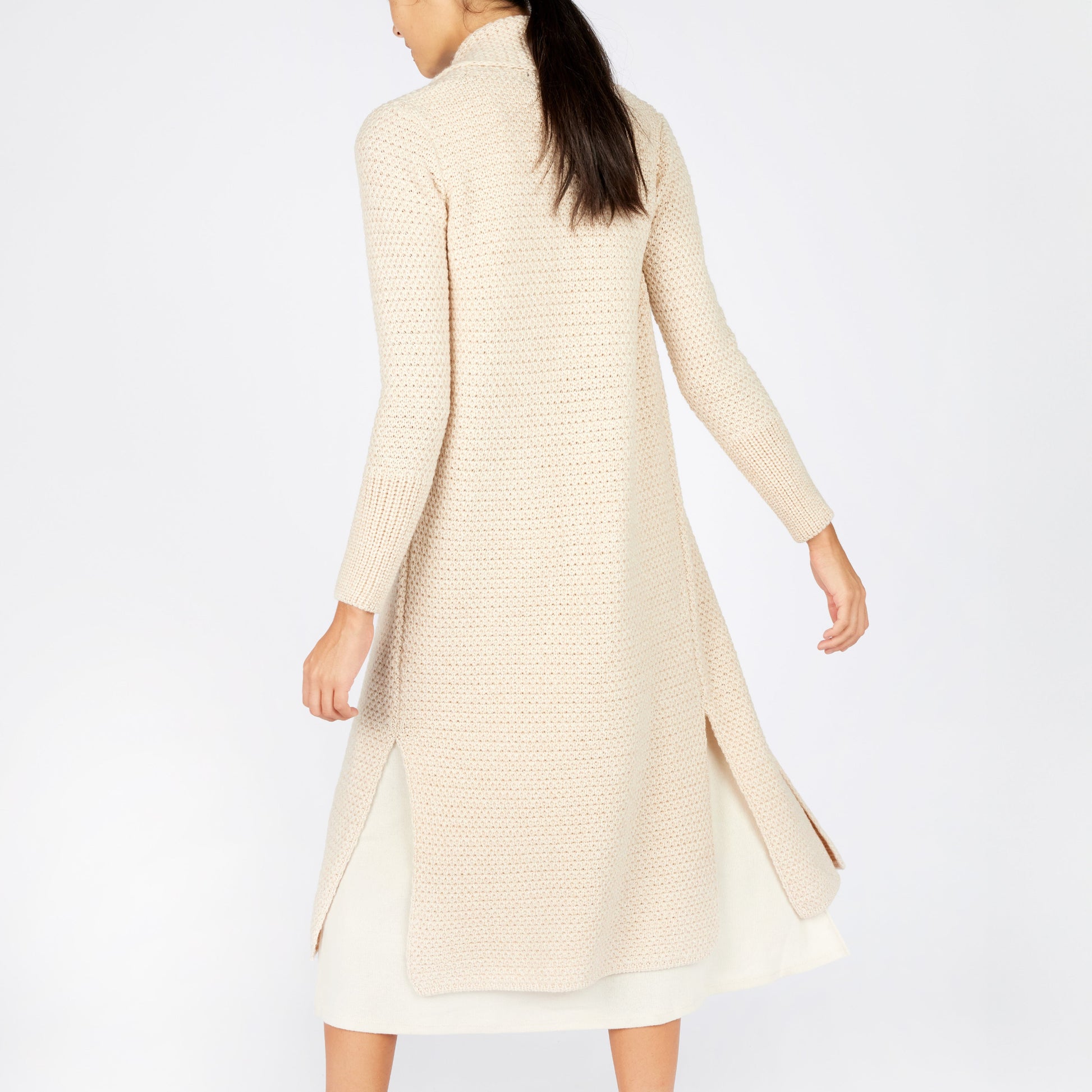 Woman wearing a long beige cardigan on a white background