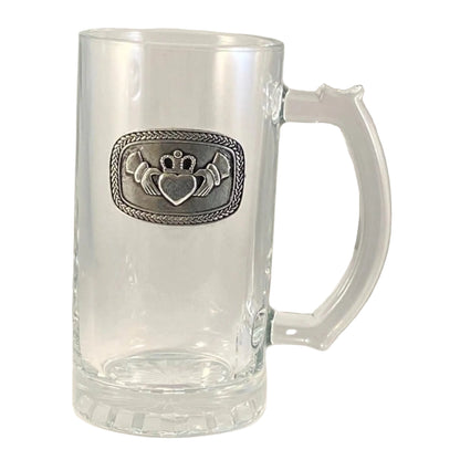 A clear glass tankard with a pewter claddagh emblem on the front. 