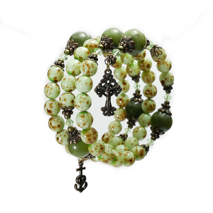 Green beaded bracelet with metal charms on a white background