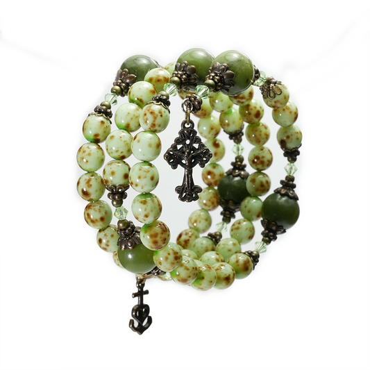 Green beaded bracelet with metal charms on a white background