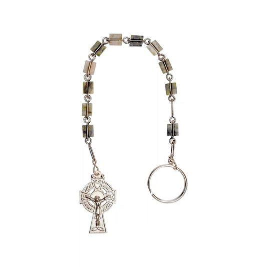 A silver-toned rosary with olive green and beige stone beads, featuring a detailed crucifix pendant and a split ring clasp, shown against a plain white background.
