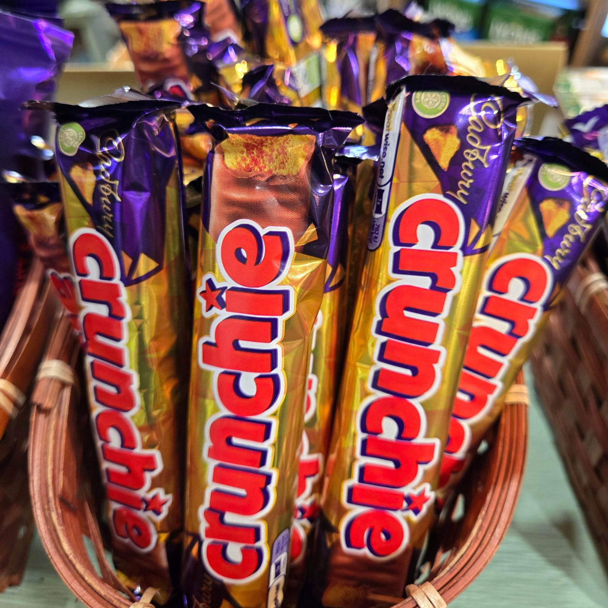 A basket filled with multiple Cadbury Crunchie chocolate bars, showing the iconic purple and gold wrapper design with red and white branding.