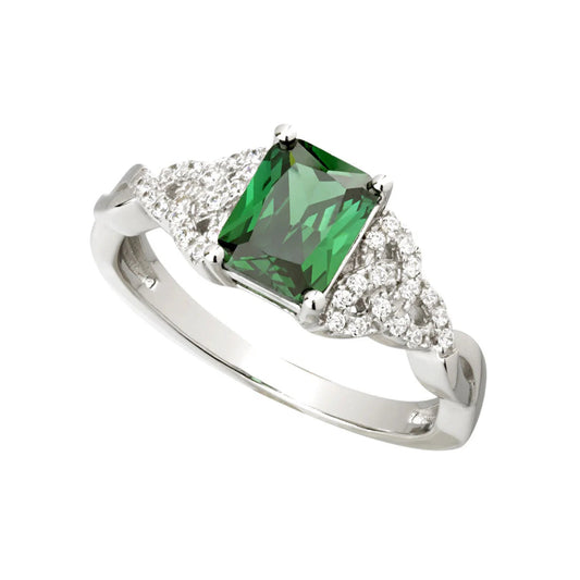 A sterling silver ring with a green cubic zirconia centerpiece. The stone is bordered on either side by trinity-shaped silver supports. The trinity knots are studded with clear white cubic zirconia stones.