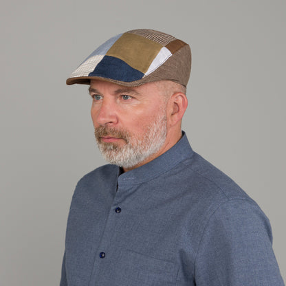 Man wearing a patchwork cap against a gray background