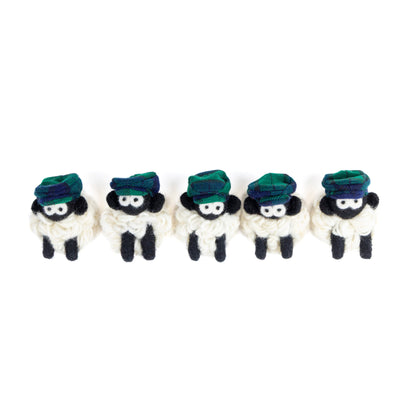 Five small knit sheep with green flat caps