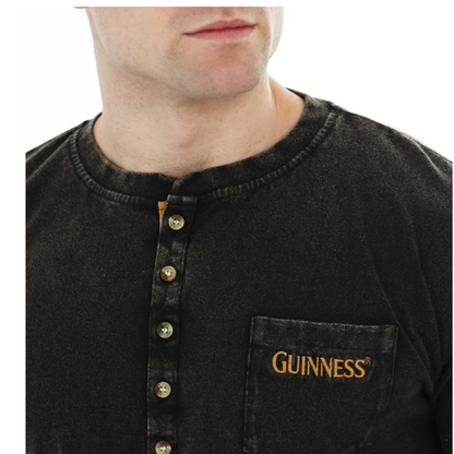 A person wearing a long sleeve black Henley t-shirt with a guinness logo on the chest pocket.