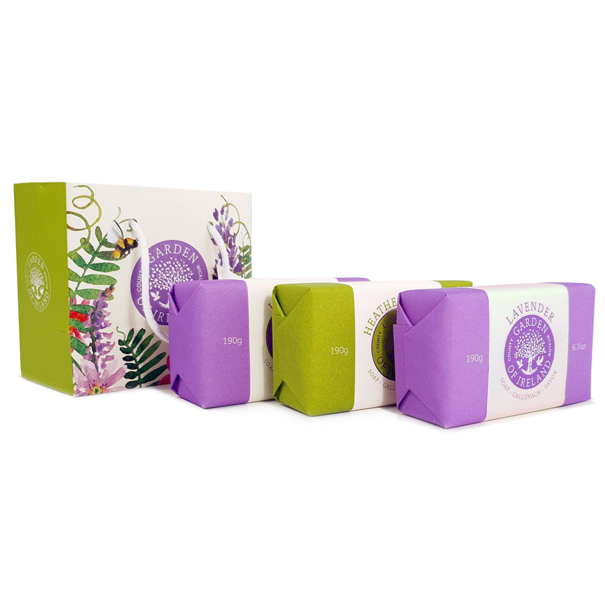 Three vibrant paper-covered bar soaps next to a floral patterned bag. 