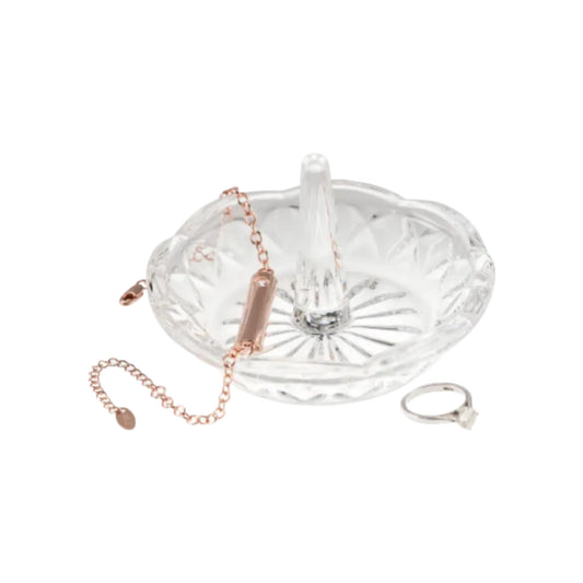Clear glass jewelry tray with rose gold bracelet and silver ring on a white background