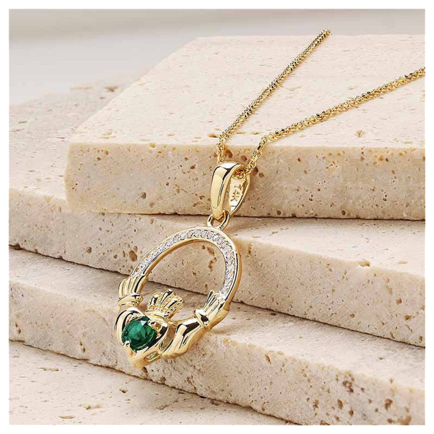 Gold claddagh necklace resting on a marble surface.