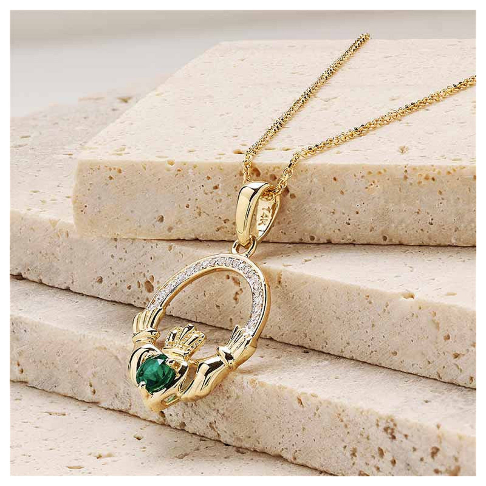 Gold claddagh necklace resting on a marble surface.